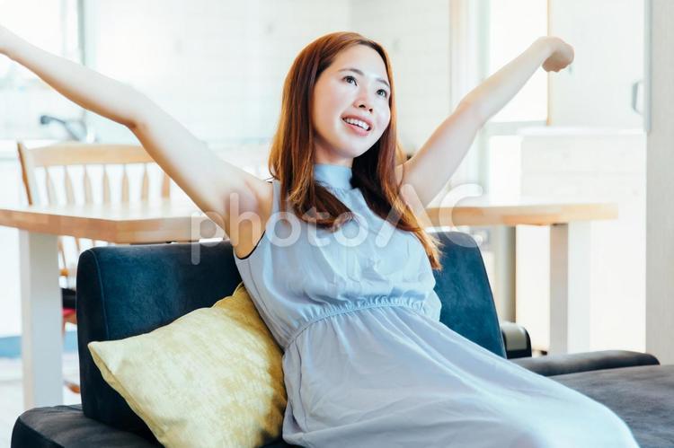 ソファの上で背伸びする女性 女性,ソファ,背伸びの写真素材