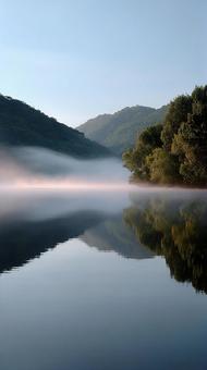 朝霧が漂う、穏やかな湖面の神秘的な風景の写真