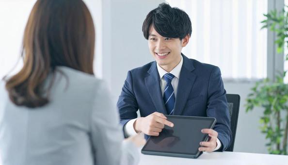タブレットを使って説明する男性営業マン タブレットを使って説明する男性営業マンの写真