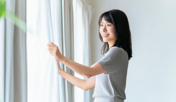 カーテンを開ける女性 カーテンを開ける女性の写真