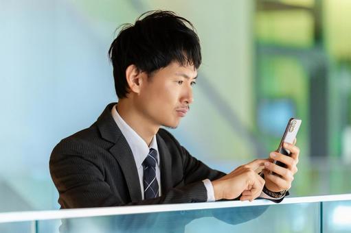 スマホの画面を見て考える男性ビジネスマン スマホの画面を見て考える男性ビジネスマン 男性,スマホ,スマートフォンの写真素材