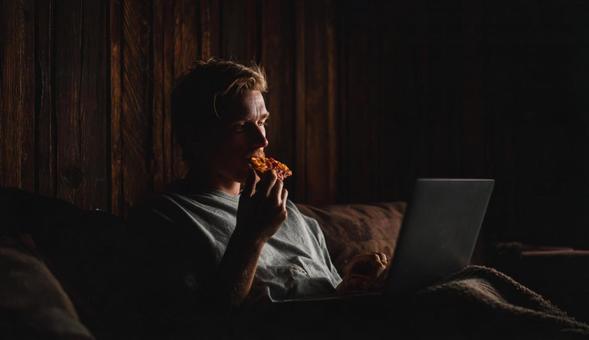 食事をしながらノートパソコンを操作する人 食事をしながらノートパソコンを操作する人の写真