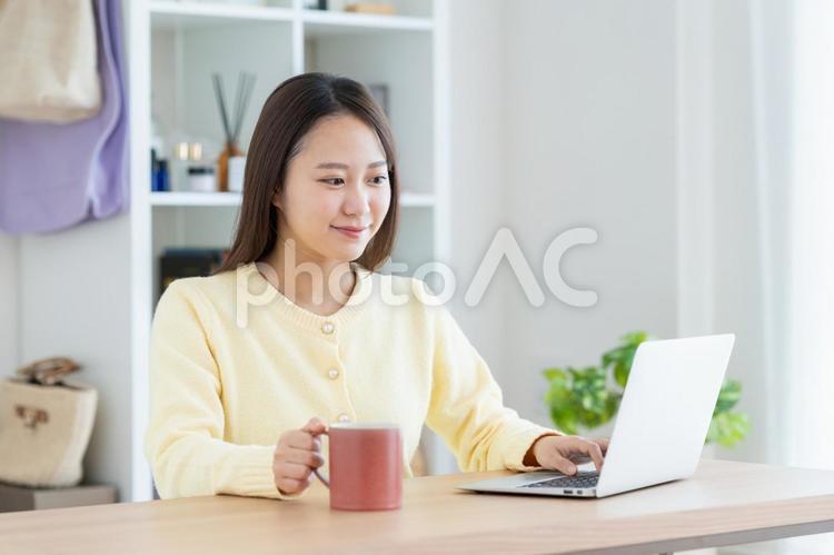 リビングでパソコンを使う若い女性 パソコン,女性,笑顔の写真素材