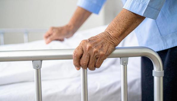 4点柵を設置したベッドに寝る高齢女性患者 4点柵を設置したベッドに寝る高齢女性患者の写真