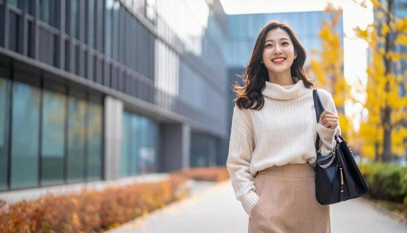 秋のオフィス街を歩く笑顔の女性 秋のオフィス街を歩く笑顔の女性の写真