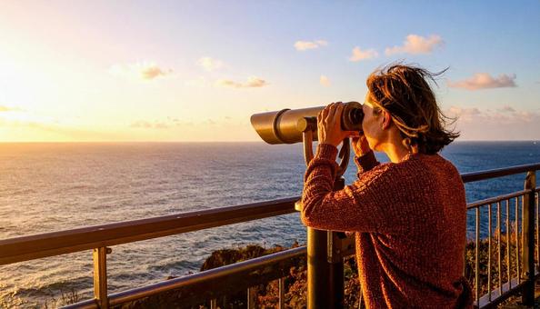 双眼鏡で海の先を見ている女性 双眼鏡で海の先を見ている女性の写真