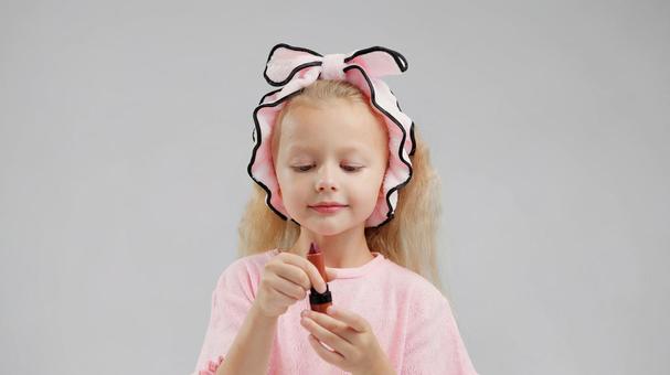 口紅を見るヘアバンドの女の子 口紅を見るヘアバンドの女の子 女の子,口紅,持つの写真素材