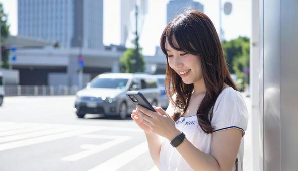 スマートフォンを操作する若い女性の写真