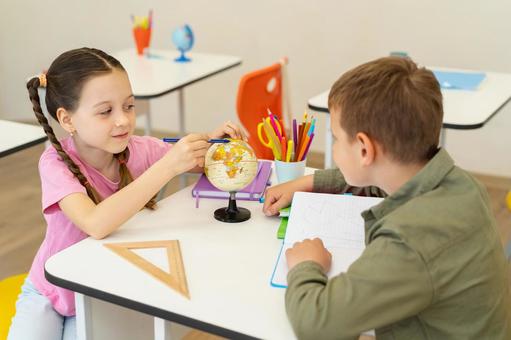 振り向いてペンで地球儀をさす女の子 男の子,女の子,子どもの写真素材