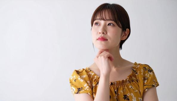 黄色い花柄ワンピースの女性が考えるポーズ 黄色い花柄ワンピースの女性が考えるポーズの写真