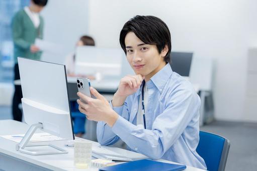 オフィスでスマホを使うビジネスマン スマホ,ビジネスマン,笑顔の写真素材