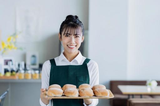 パンを持つカフェで働く若い女性 パンを持つカフェで働く若い女性 女性,ベーカリー,パンの写真素材