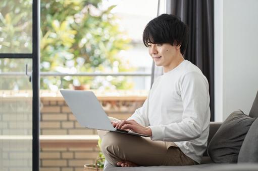 A man using a computer in his living room, laptop, male, living, JPG