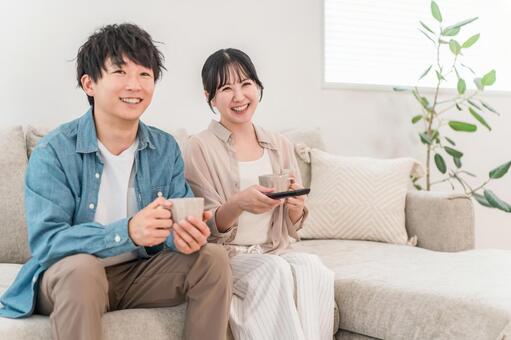 ソファーでテレビを見てくつろぐ若い夫婦 夫婦,カップル,ソファーの写真素材