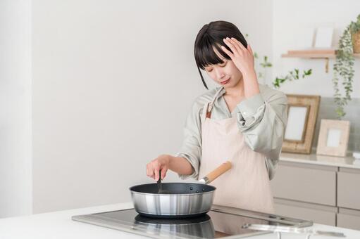 キッチンで悩む,料理するエプロン姿の女性 キッチン,料理,失敗の写真素材