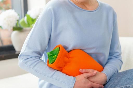 生理痛でお腹を湯たんぽで温めている女性 生理,月経,女性の写真素材