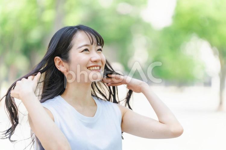 緑の中で黒髪をなびかせる女性（ヘアケア） 髪,ヘア,なびかせるの写真素材