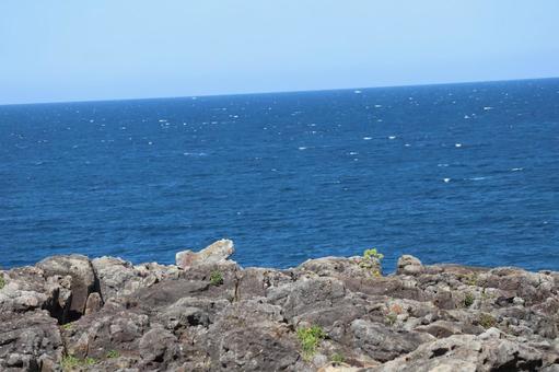 岩場と青い海面の海と地平線と青空の風景 岩場と青い海面の海と地平線と青空の風景の写真