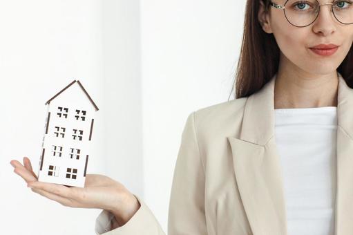 女性スタッフと手のひらの家の模型 保険業,事務職,接客業の写真素材