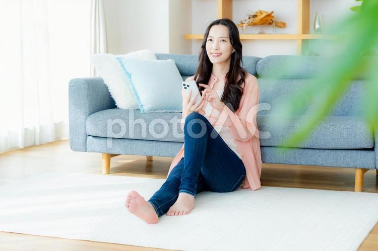 部屋でスマホを操作する女性 スマホ,笑顔,女性の写真素材