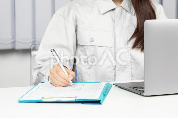 作業着でPC操作しメモをする女性03 女性,メモ,書くの写真素材