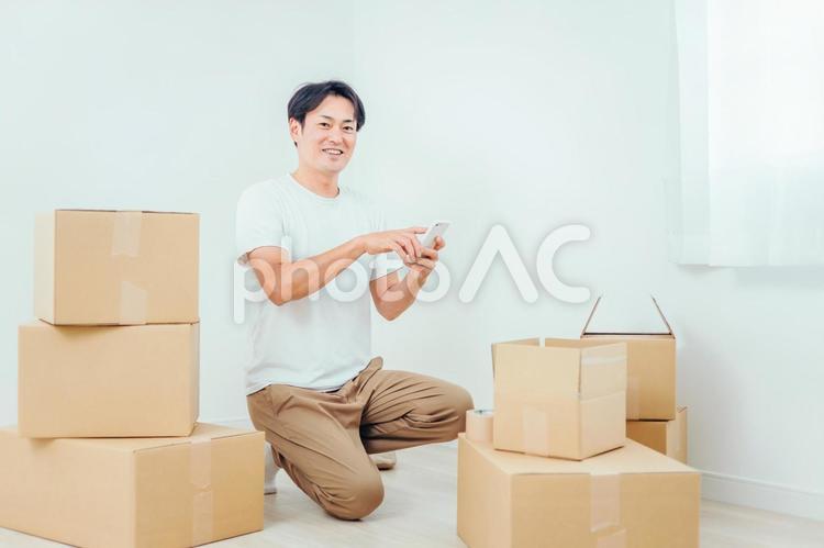 ダンボールとスマホを使う男性 引越し,スマホ,荷造りの写真素材