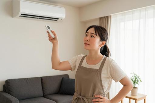 エアコンを操作する主婦の写真