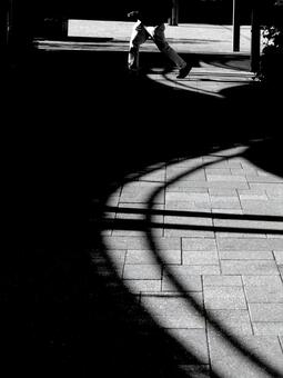 光のアーチと足早に過ぎ去る人の影 モノクロ,白黒,光と影の写真素材
