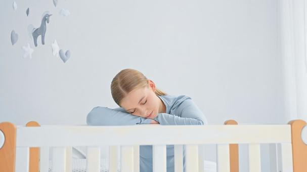 ベッドの柵で腕枕をして寝る女性 ベッドの柵で腕枕をして寝る女性の写真