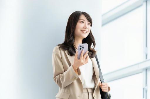スマホを持つ笑顔の女性・ビジネスウーマン スマホを持つ笑顔の女性・ビジネスウーマン 女性,スマホ,スマートフォンの写真素材