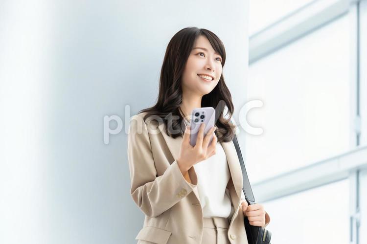 スマホを持つ笑顔の女性・ビジネスウーマン 女性,スマホ,スマートフォンの写真素材