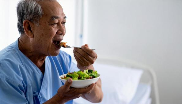 端座位で食事をするシニア男性の患者の写真