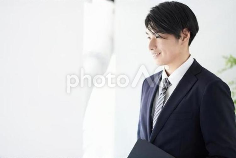 笑顔で窓の外を見る日本人男性ビジネスマン 笑顔,男性,ビジネスマンの写真素材