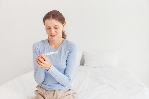 微笑んで体温計を見る女性 微笑んで体温計を見る女性の写真