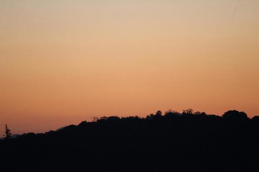 黒いシルエットの山とオレンジ色の夕空 黒いシルエットの山とオレンジ色の夕空の写真