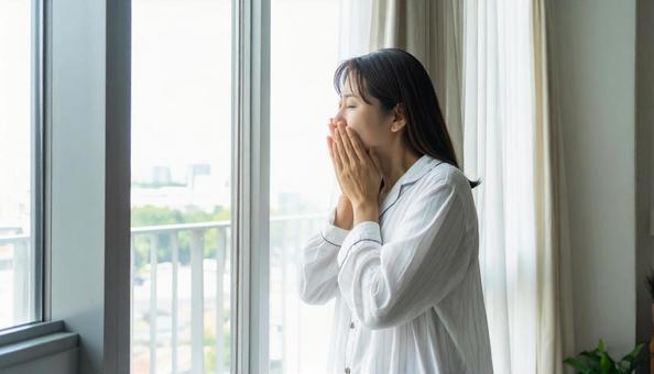 部屋着のまま部屋の窓際で体調不良の女性 部屋着のまま部屋の窓際で体調不良の女性の写真