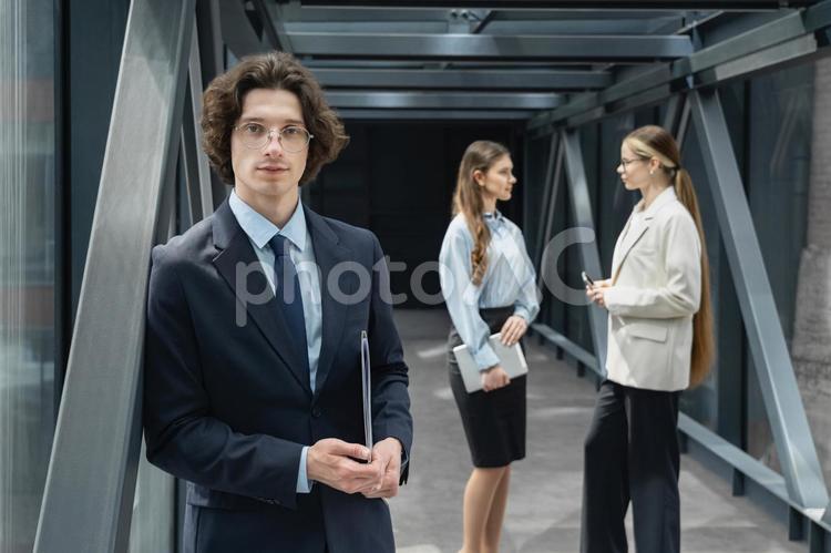 オフィスの渡り廊下で立ち話する女性たちとカメラ目線の男性 ビジネス,グループ,ビジネスマンの写真素材