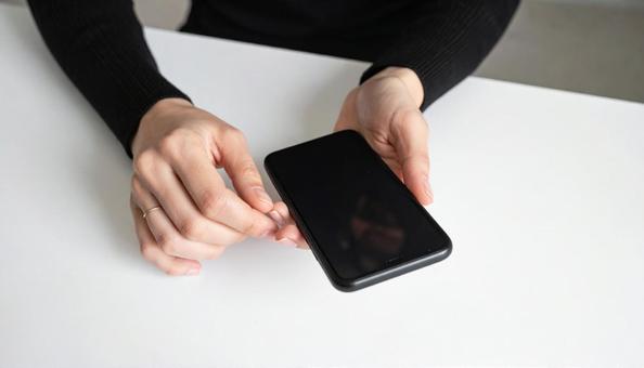 携帯を操作する女性の手元とノートパソコン 携帯を操作する女性の手元とノートパソコンの写真
