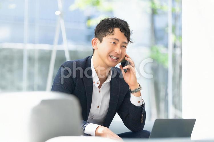 スマホで通話をする笑顔の男性ビジネスマン 男性,スマホ,スマートフォンの写真素材