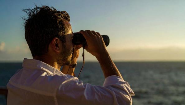 双眼鏡で海の先を見ている日本人男性 双眼鏡で海の先を見ている日本人男性の写真