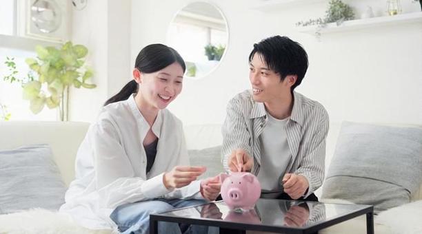 貯金箱にお金を入れるアジア人のカップル 貯金箱にお金を入れるアジア人のカップル 貯金,カップル,女性の写真素材