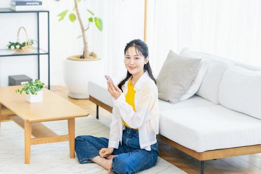 部屋でスマホを操作する女性 スマホ,笑顔,部屋の写真素材
