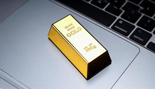 パソコンに置かれた金の延べ棒のミニチュア パソコンに置かれた金の延べ棒のミニチュアの写真