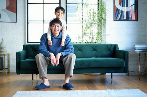 ソファーに座る男性の後ろにいる男の子 ソファーに座る男性の後ろにいる男の子 親子,男の子,小学生の写真素材