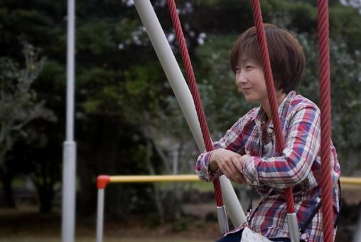 ＜素材＞夕暮れ公園でブランコで遊ぶ女性 女性,笑顔,ブランコの写真素材
