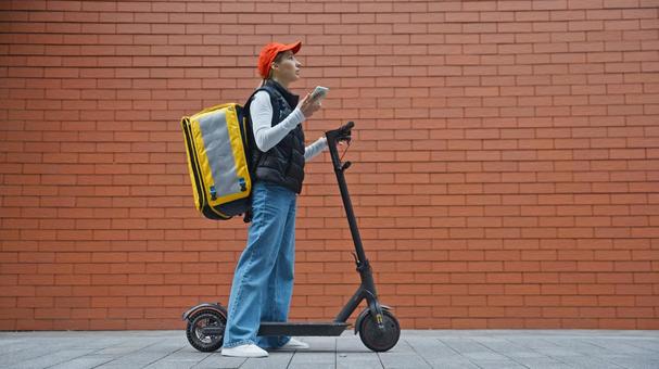 電動キックボードとフードデリバリーの女性 配達,フードデリバリー,デリバリーの写真素材