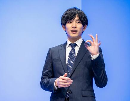 ステージ上で堂々とプレゼンする男性 ステージ上で堂々とプレゼンする男性の写真