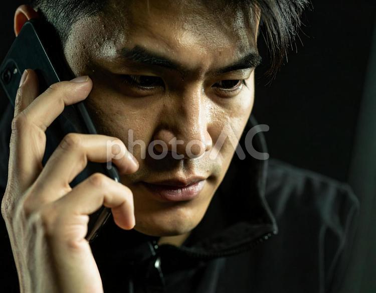暗闇で電話する詐欺の男性 男性,犯罪,詐欺の写真素材
