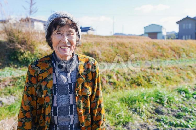 田舎でほほえむ高齢の女性 お洒落,田んぼ,笑うの写真素材