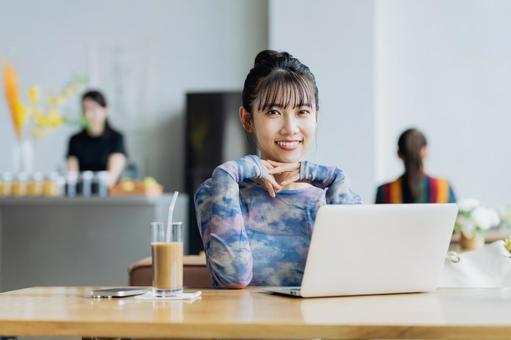 カフェで仕事をするフリーランスの若い女性 カフェで仕事をするフリーランスの若い女性の写真